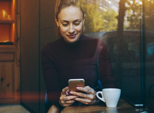 Low-Cost Mortgages - Woman at coffee shop looking at phone