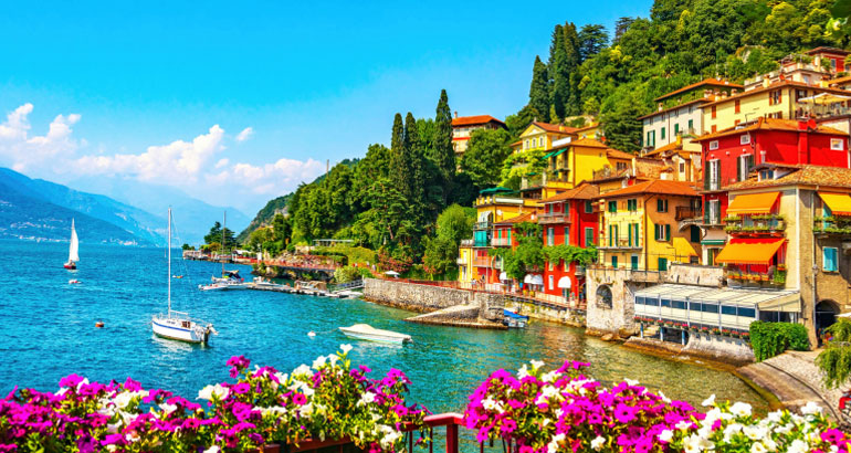 Sailboats in Lake Como with buildings in the background and beautiful flowers