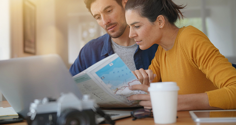 Couple planning trip at home with map and laptop