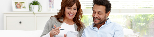 couple sitting on white couch reviewing notepad woman is holding