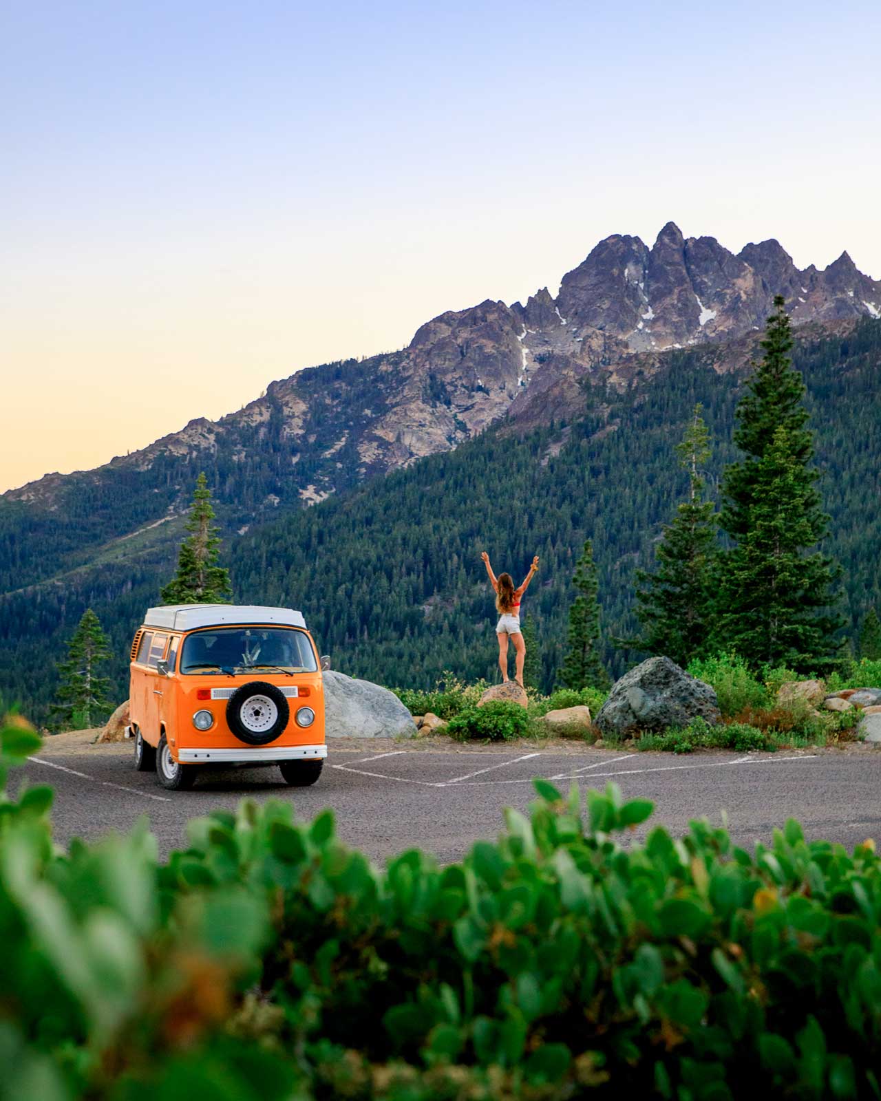 A camper van by a mountain with a woman outside
