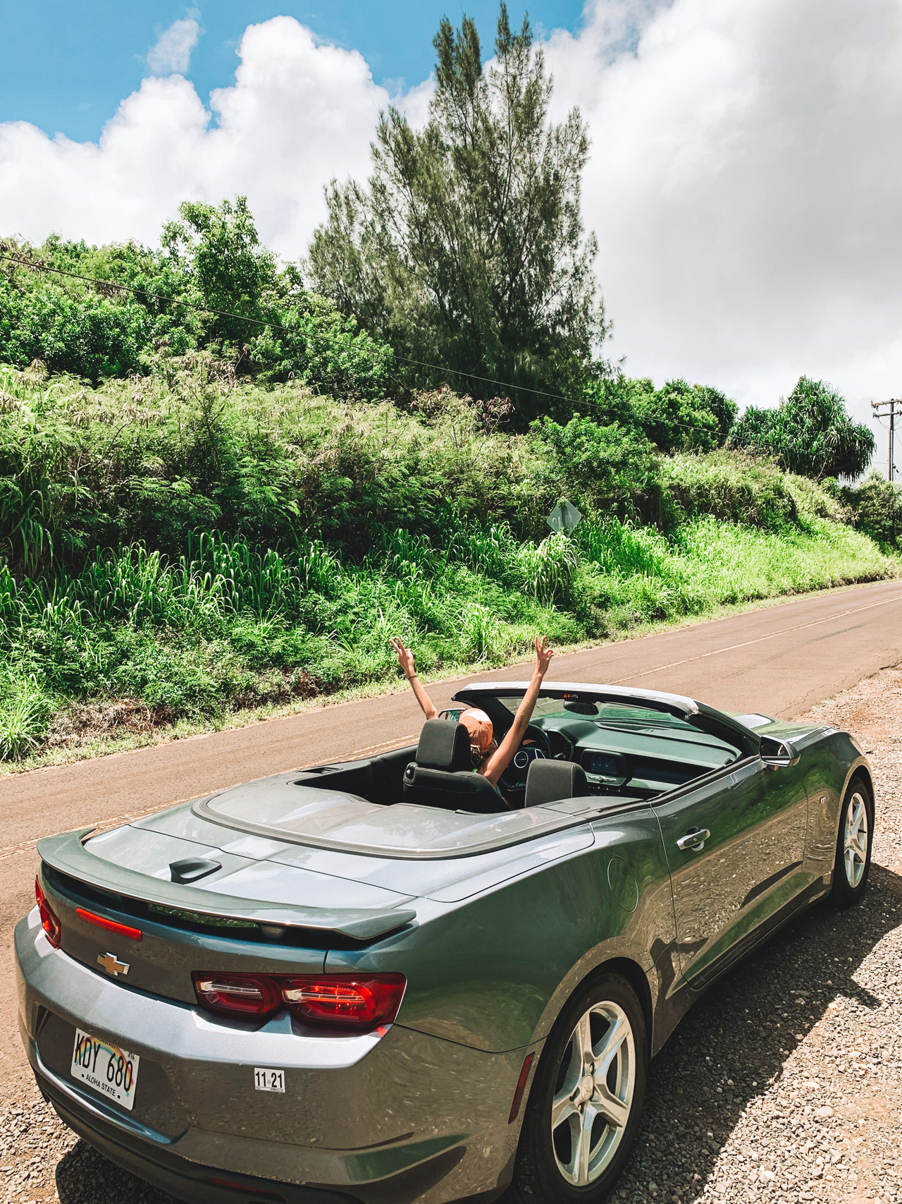 Convertible car on dirt road with lone driver