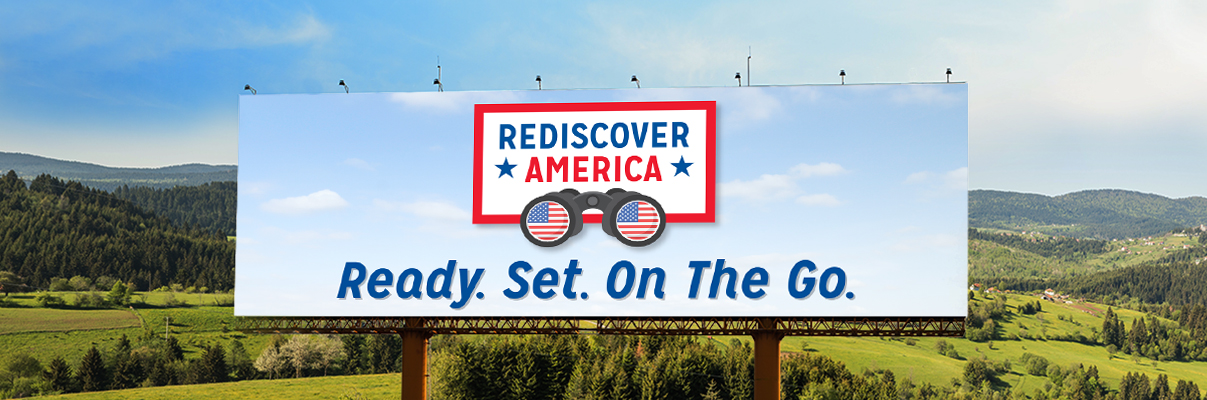 USA Road Trips with AAA and billboard with rolling hills behind it