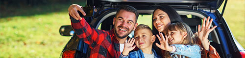 Family sitting in back of car taking a selfie with T-Mobile phone