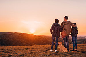 Family standing on hillside watching sunset