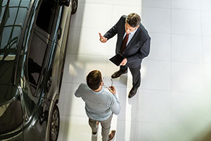 Two people standing beside car discussing purchasing vehicle 