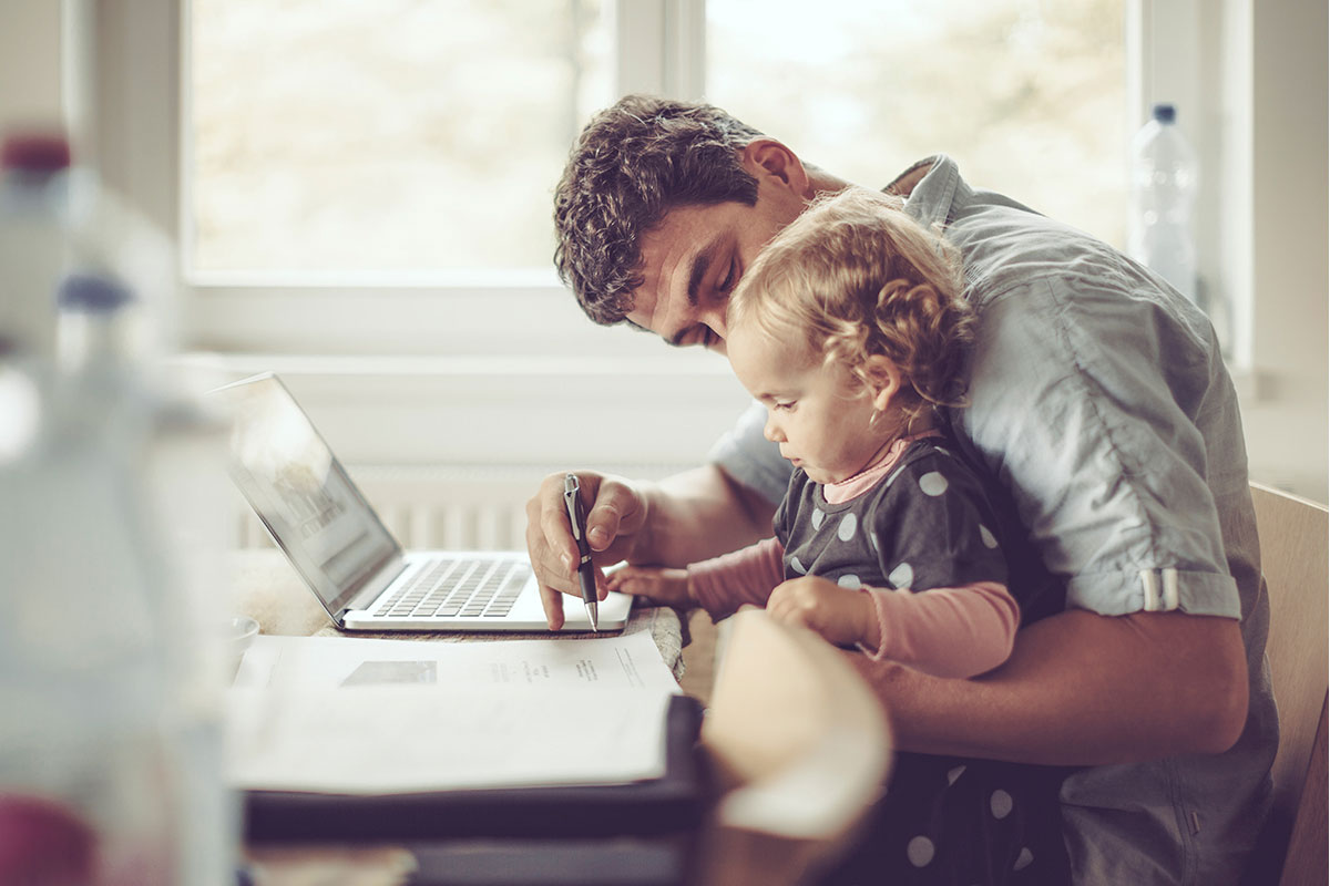 Father holding baby sitting in front of laptop