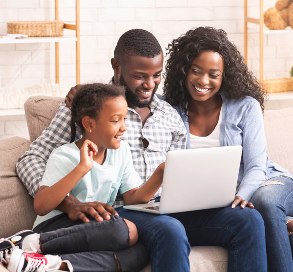 A young family looking at infomation on a laptop in their living room.