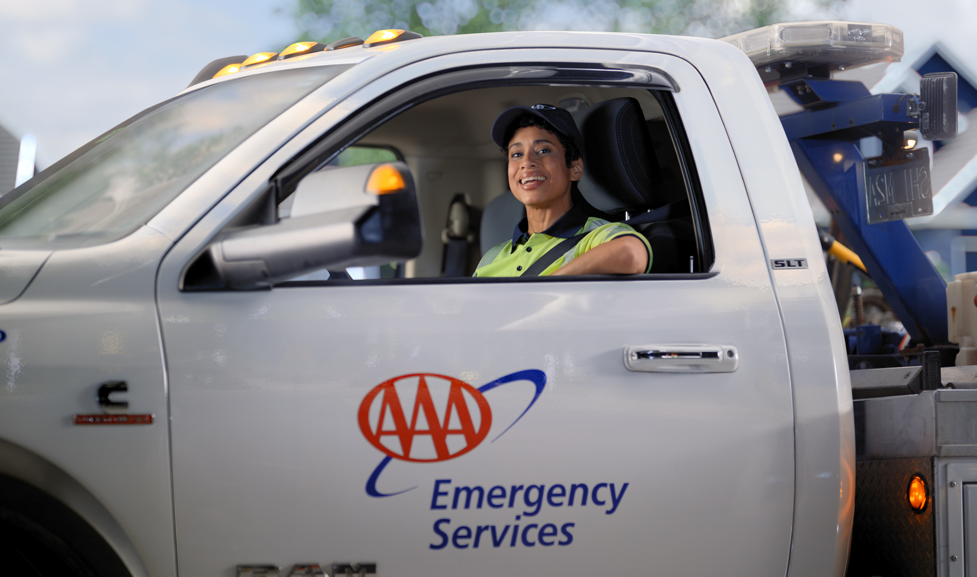 A woman emergency roadside assistance driver leaning out of the window of an AAA truck.