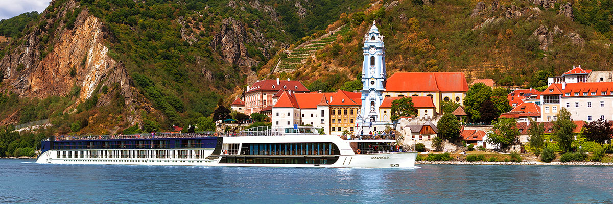 AmaWaterways river cruise ship sailing in front of red roofed buildings