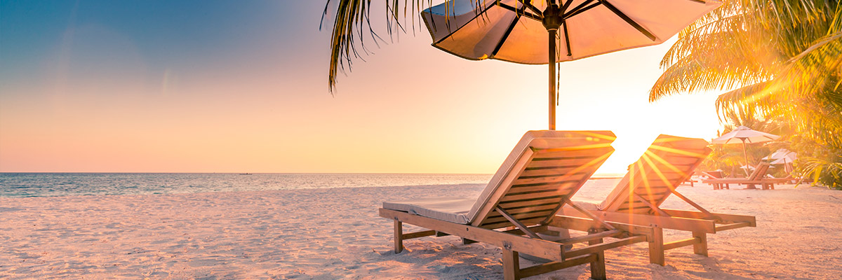 Open beach chairs under umbrella during sunset